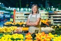 Portrait of a senior gray-haired woman of a supermarket worker, worker spreads fruit with crossed arms smiles and looks at camera Royalty Free Stock Photo