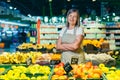 Portrait of a senior gray-haired woman of a supermarket worker, worker spreads fruit with crossed arms smiles and looks at camera Royalty Free Stock Photo