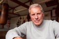 Portrait Of Senior Male Boxing Coach In Gym Standing By Old Fashioned Leather Punching Bags Royalty Free Stock Photo