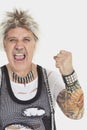 Portrait of senior male punk screaming with clenched fist over gray background Royalty Free Stock Photo