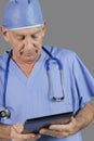 Portrait of senior male surgeon holding tablet PC over gray background Royalty Free Stock Photo