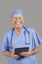Portrait of senior male surgeon holding tablet PC over gray background Royalty Free Stock Photo
