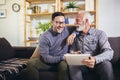 Senior man with adult son using digital tablet at home Royalty Free Stock Photo