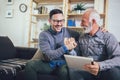 Senior man with adult son using digital tablet at home Royalty Free Stock Photo