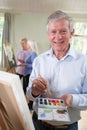 Portrait Of Senior Man Attending Painting Class With Teacher In Background Royalty Free Stock Photo