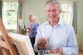 Portrait Of Senior Man Attending Painting Class With Teacher In Background Royalty Free Stock Photo