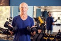 A portrait of senior man in the gym training with dumbbells. People, health and lifestyle concept