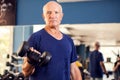 A portrait of senior man in the gym training with dumbbells. People, health and lifestyle concept