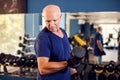 A portrait of senior man in the gym training with dumbbells. People, health and lifestyle concept