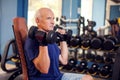 A portrait of senior man in the gym training with dumbbells. People, health and lifestyle concept