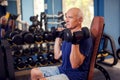 A portrait of senior man in the gym training with dumbbells. People, health and lifestyle concept