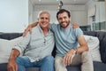 Portrait of a senior man with his adult son relaxing on a sofa together in the living room. Happy, smile and elderly Royalty Free Stock Photo