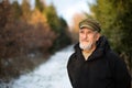 Portrait of a senior man, outdoor on a snowy forest path