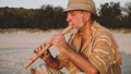 Portrait of senior man playing bamboo flute on the beach next to fishing boat Royalty Free Stock Photo