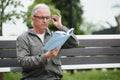 Portrait of senior man reading on bench during summer day. Royalty Free Stock Photo