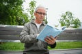 Portrait of senior man reading on bench during summer day. Royalty Free Stock Photo