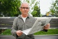 Portrait of senior man reading on bench during summer day. Royalty Free Stock Photo