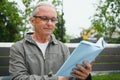 Portrait of senior man reading on bench during summer day. Royalty Free Stock Photo