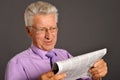 Portrait of senior man reading newspaper on gray Royalty Free Stock Photo