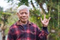 Portrait of a senior man with short gray hair showing fingers I love you a symbol, smliling, and looking at the camera Royalty Free Stock Photo