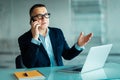 Portrait of a senior man smiling in suit with a phone and a laptop computer in office Royalty Free Stock Photo