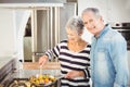 Portrait of senior man standing with wife cooking food