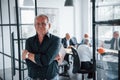 Portrait of senior man that stands in front of aged team of elderly businessman architects that have a meeting in the