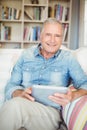 Portrait of senior man using tablet while sitting on sofa Royalty Free Stock Photo