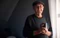 Portrait Of Senior Man Wearing Cap Relaxing Standing By Window At Home With Hot Drink Royalty Free Stock Photo