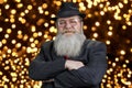 Portrait of senior man wearing suit and hat posing at camera with crossed arms. Royalty Free Stock Photo