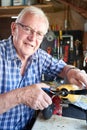 Portrait Of Senior Man Working On Model Radio Controlled Aeroplane In Shed At Home