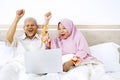 Senior couple lifting hands together on bed