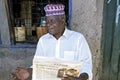 Portrait senior reading old newspaper for liquor store