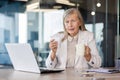 Portrait of senior sick businesswoman at workplace, female boss looking upset at camera holding cup of hot drink and