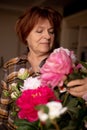 Portrait of senior smiling woman with dark hair wearing checkered shirt, holding bouquet of pink, white roses flowers. Royalty Free Stock Photo