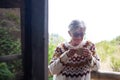 Portrait of senior smiling woman outdoor on balcony wearing winter sweater and drinking a cup of tea. Relaxed elderly woman gray Royalty Free Stock Photo