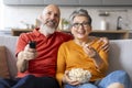 Portrait Of Senior Spouses Watching Tv At Home And Eating Popcorn Royalty Free Stock Photo