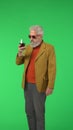 Portrait of senior stylish hipster on Chroma key green screen background, elegant man holding glass of wine. Advertising Royalty Free Stock Photo