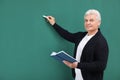 Portrait of senior teacher with book and chalk at green board Royalty Free Stock Photo