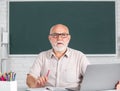 Portrait of senior teacher teaching line of high school students with computer laptop in classroom on blackboard. Adult Royalty Free Stock Photo