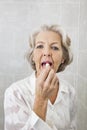 Portrait of senior woman applying lipstick in bathroom Royalty Free Stock Photo