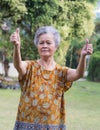 Portrait of a senior woman with arms raised, smiling, and looking at the camera while standing in a garden. Concept of aged people Royalty Free Stock Photo