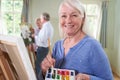 Portrait Of Senior Woman Attending Painting Class With Teacher          In Background Royalty Free Stock Photo