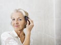 Portrait Of Senior Woman Brushing Hair In Bathroom