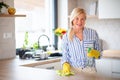 Portrait of senior woman cleaning kitchen counter indoors at home. Royalty Free Stock Photo