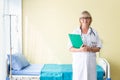 Portrait senior woman doctor standing holding folder with stethoscope. Royalty Free Stock Photo