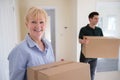 Portrait Of Senior Woman Downsizing In Retirement Carrying Boxes Into New Home On Moving Day With Removal Man Helping Royalty Free Stock Photo