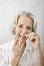 Portrait of senior woman flossing teeth in bathroom Royalty Free Stock Photo
