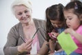 Portrait of senior woman helping granddaughters in making handicrafts at home Royalty Free Stock Photo