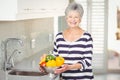 Portrait of senior woman holding colander with vegetables